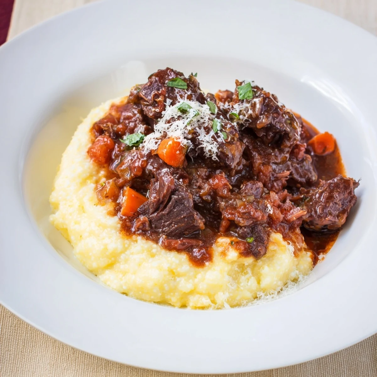 A close-up of tender Creamy Polenta with Braised Beef Short Ribs, drizzled with rich sauce.