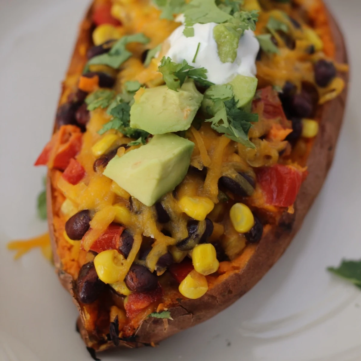 Crisp-edged Loaded Sweet Potato Skins with Black Beans, garnished with sour cream and green onions, served hot as a vegetarian appetizer.