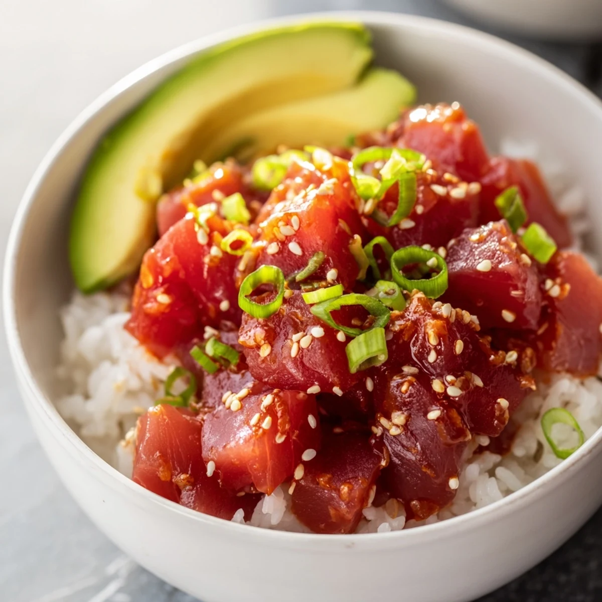 A close-up of the Spicy Tuna Roll Bowl highlights diced tuna, edamame, and sesame seeds on rice.