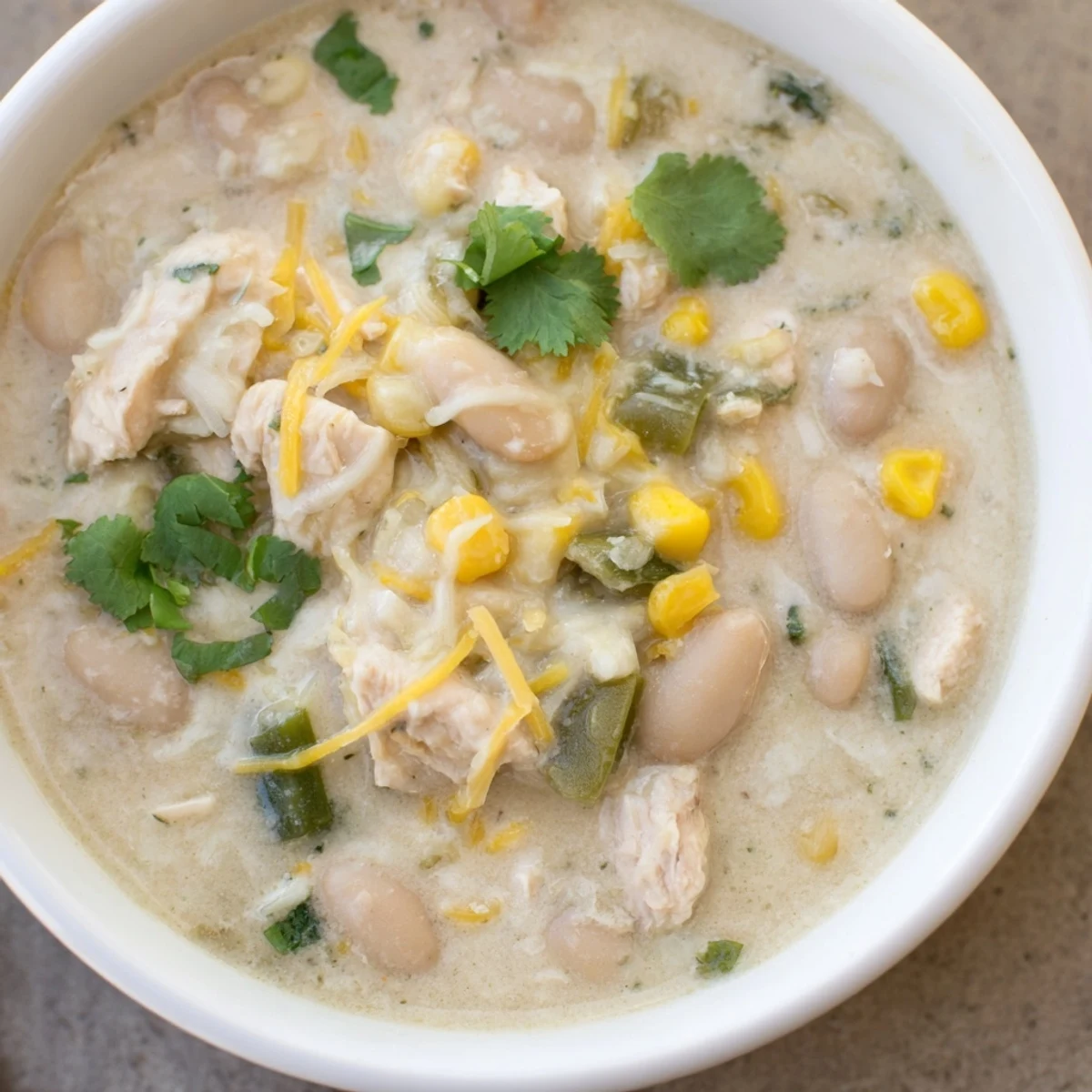 Creamy White Chicken Chili with corn and beans served steaming hot, garnished with cilantro and avocado.