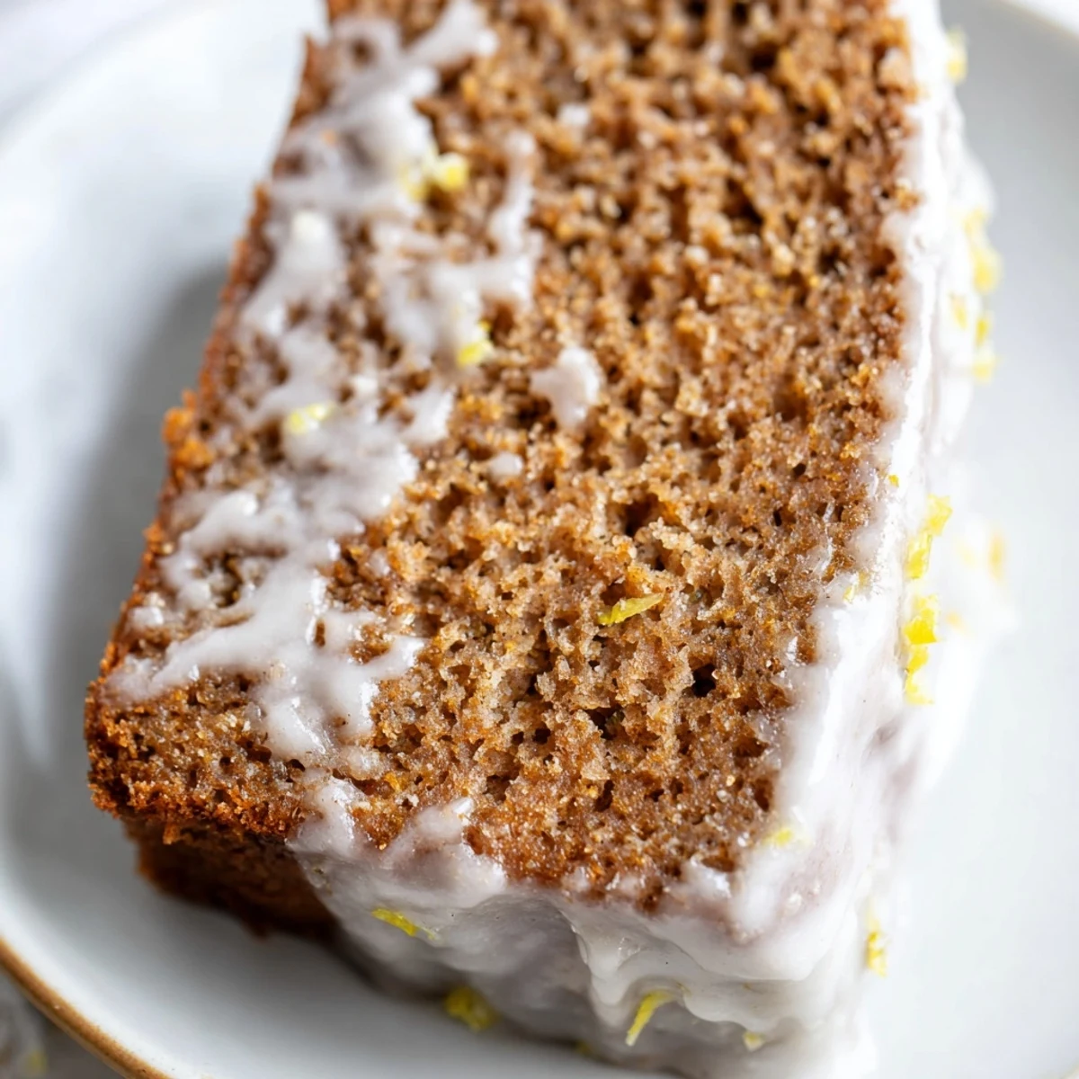 A freshly baked Gingerbread Loaf with Lemon Cream Cheese Glaze drizzled over the top, served on a wooden cutting board.