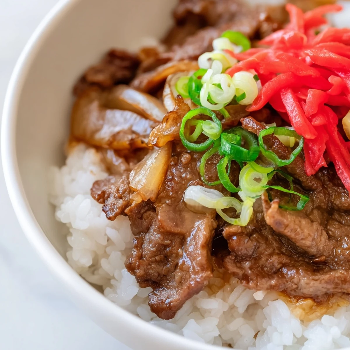 Steaming Japanese Beef Bowl with Rice, garnished with green onions and tender beef slices.