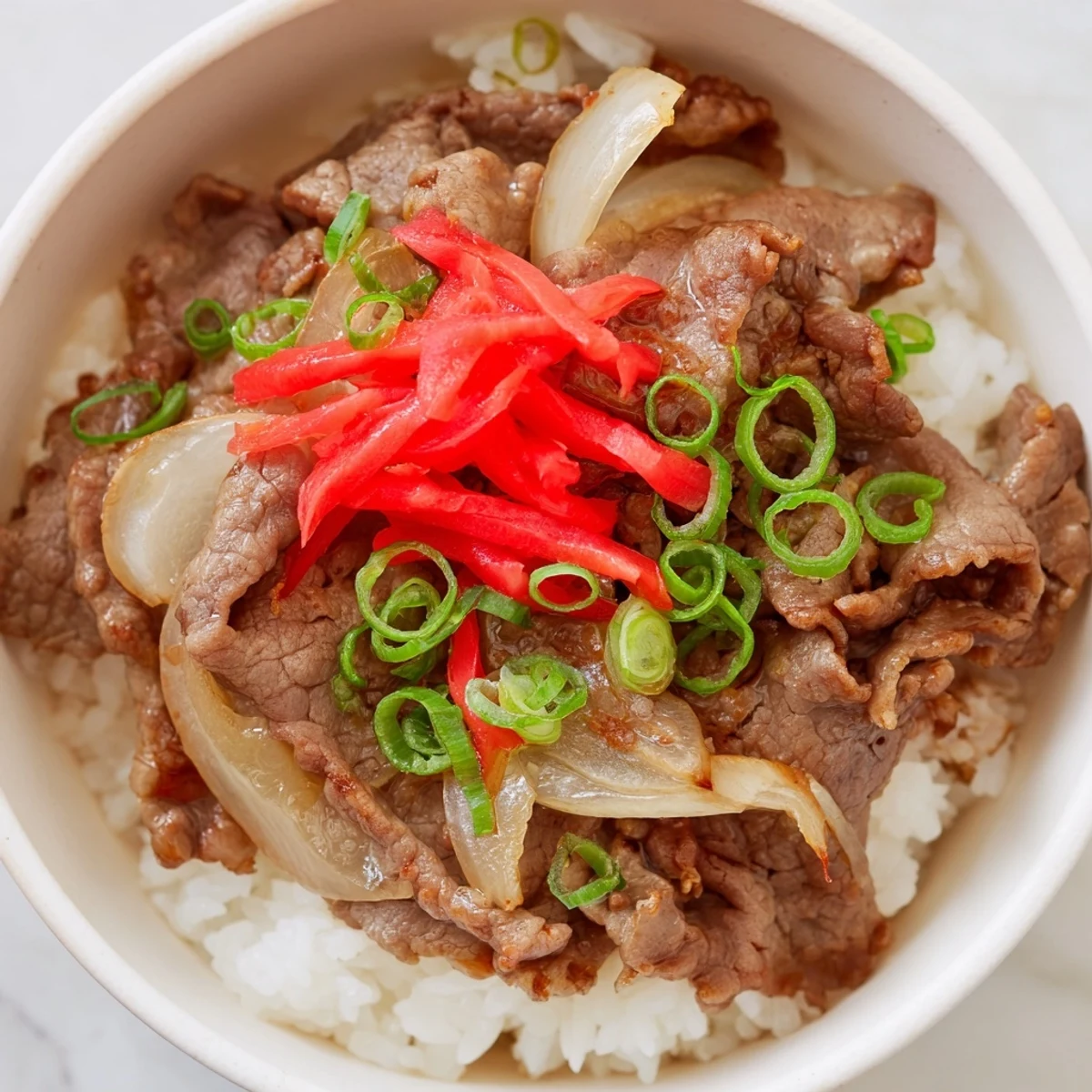 Plated Japanese Beef Bowl with Rice topped with pickled ginger, ready to enjoy with chopsticks.