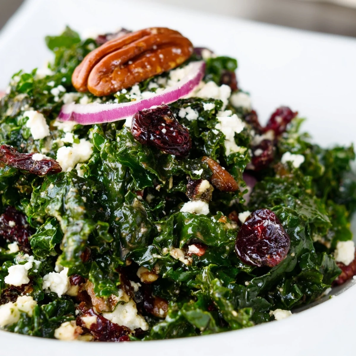 Close-up of Winter Kale Salad with Pecans and Cranberries showing toasted nuts and dried berries on massaged greens.