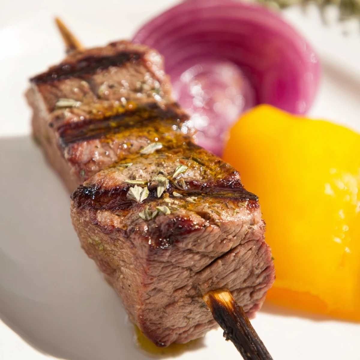 Golden-brown Beef Kebabs with Bell Peppers and Red Onion sizzling on a grill, releasing aromatic smoke over the charred vegetables.