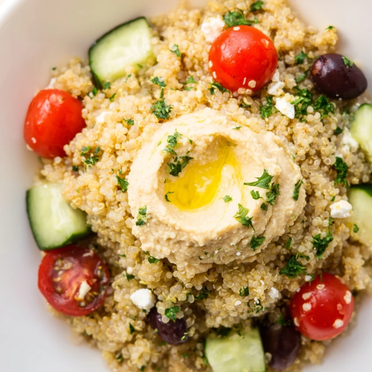 A colorful Mediterranean Quinoa Bowl topped with creamy hummus, cherry tomatoes, cucumbers, and feta, served as a wholesome, gluten-free lunch.