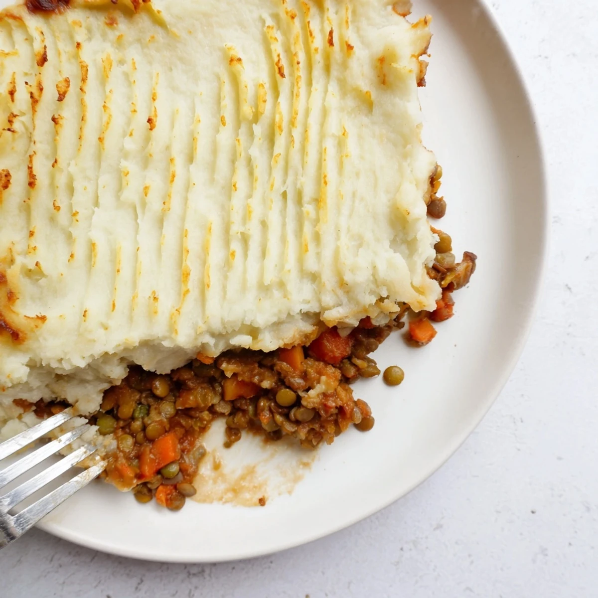A rustic serving of Vegan Lentil Shepherds Pie with Fluffy Mash on a plate, paired with a crisp green salad for a comforting, plant-based family dinner.