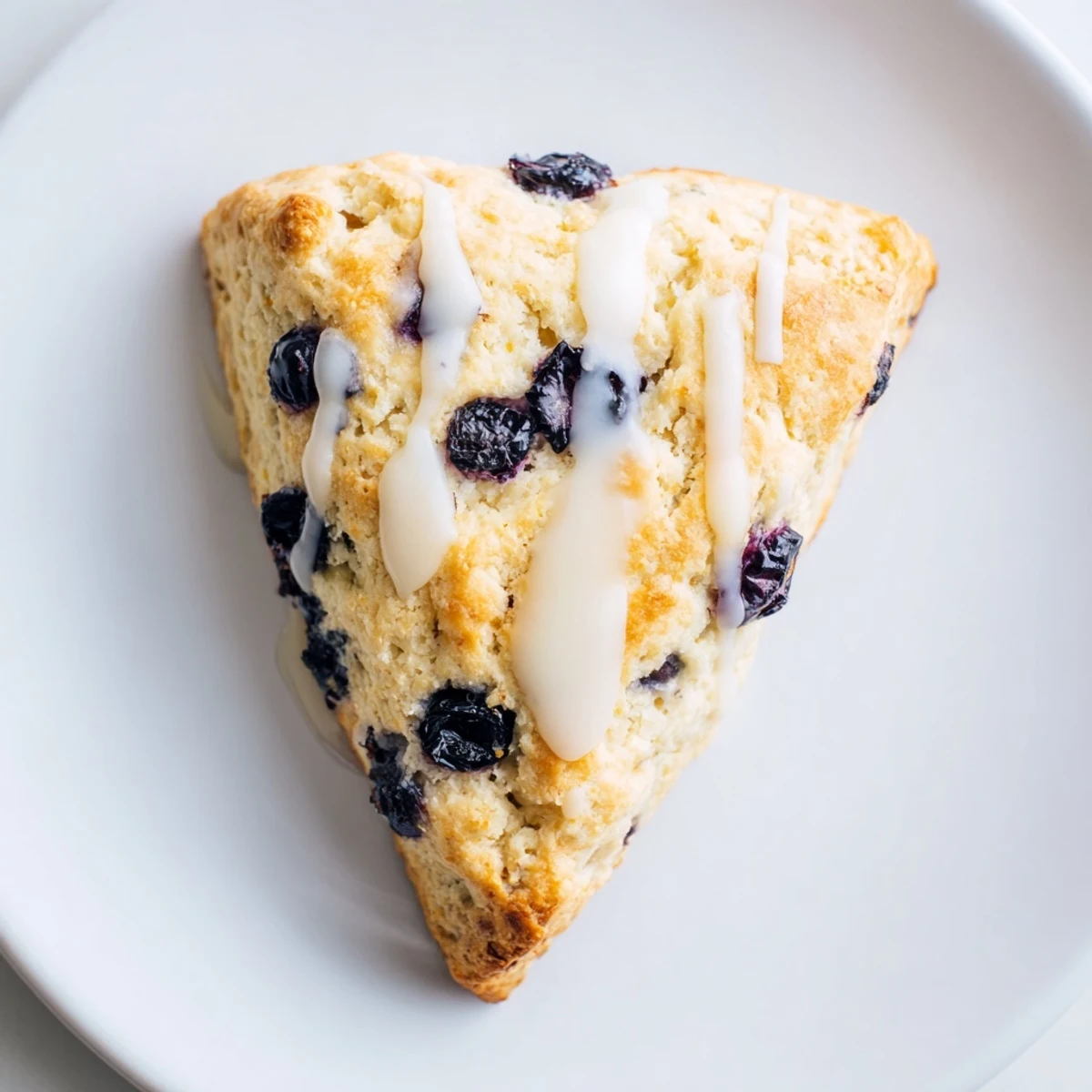 A close-up view of Lemon Blueberry Scones with Vanilla Glaze, highlighting the tender crumb texture and bright blue fruit filling.