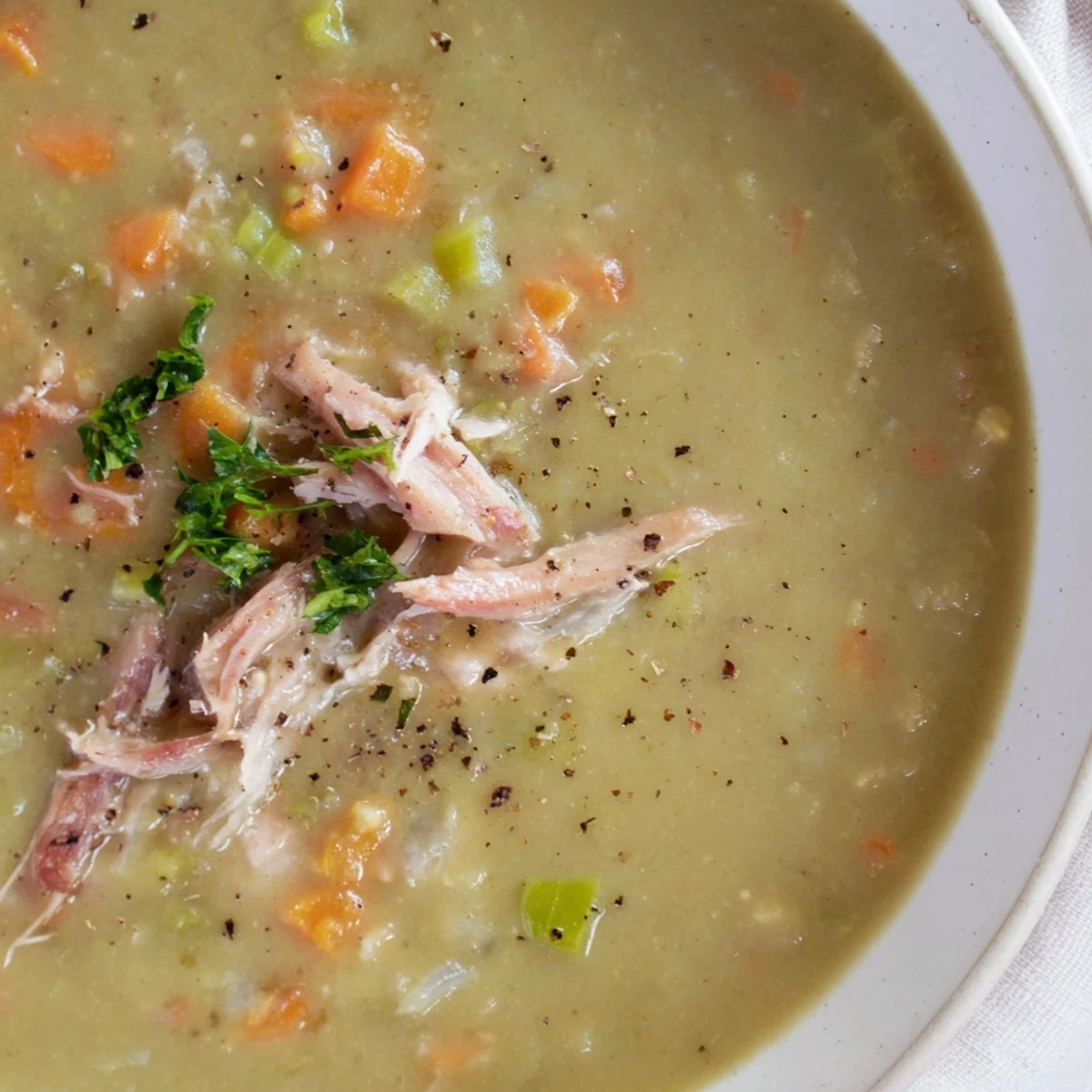 A hearty bowl of Green Split Pea Soup with Smoked Turkey, steaming with tender peas and savory herbs.