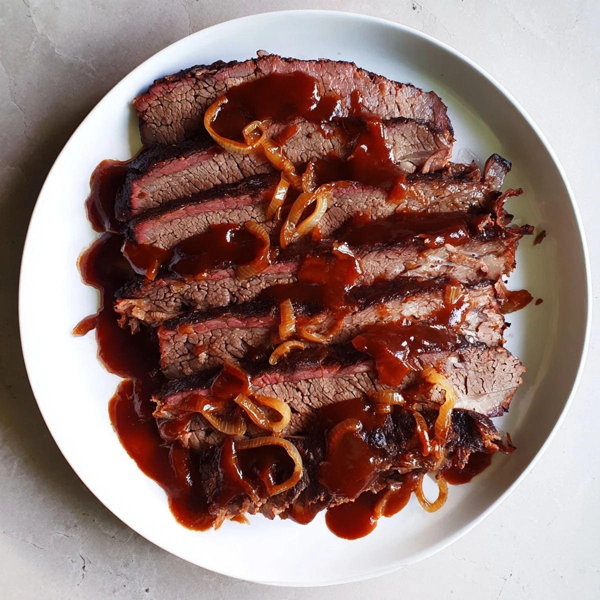 A sliced Slow Cooked Beef Brisket with BBQ Sauce shows tender, juicy meat with a smoky glaze, served on a wooden board.