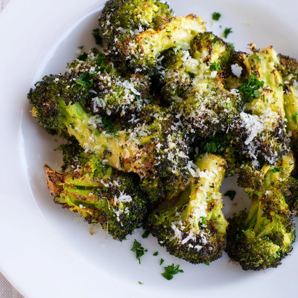 Fresh roasted broccoli with garlic and parmesan garnished with parsley, highlighted by crispy edges and savory aroma.