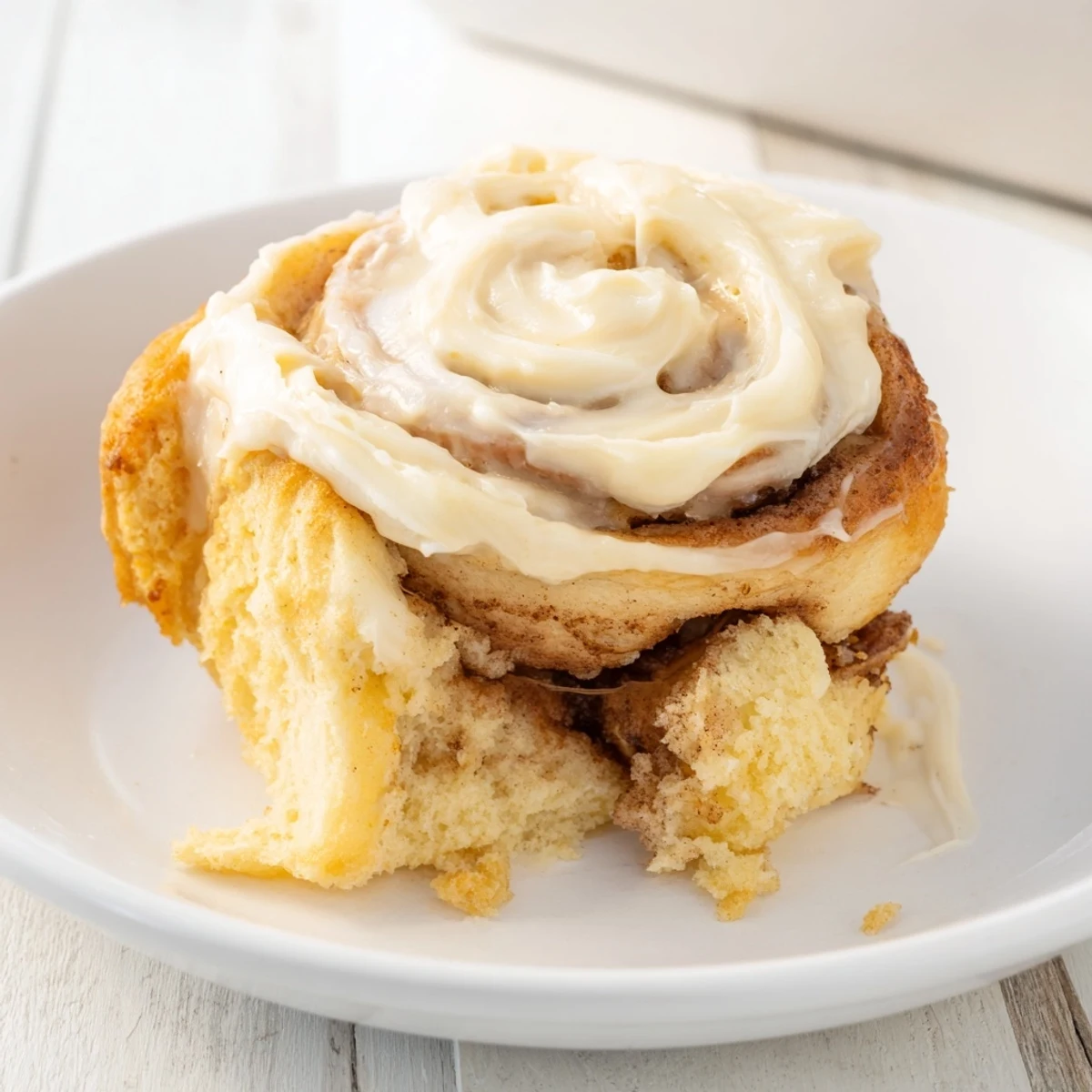 A freshly baked Keto Cinnamon Bun with cream cheese icing, perfectly sliced to reveal its tender crumb.