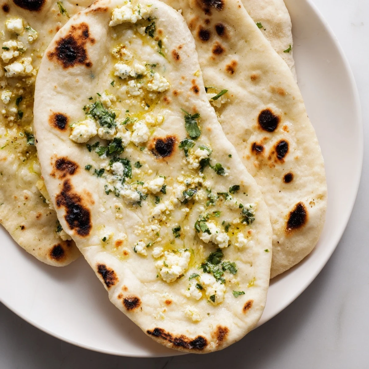Golden-brown Cottage Cheese Garlic Naan brushed with melted butter and fresh herbs on a wooden board.