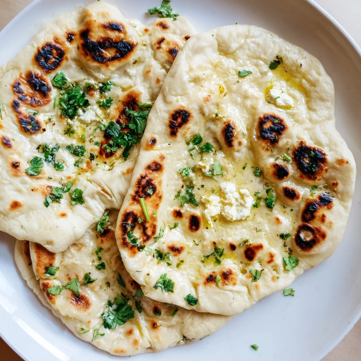 Warm Cottage Cheese Garlic Naan served alongside a bowl of creamy curry for a complete meal.