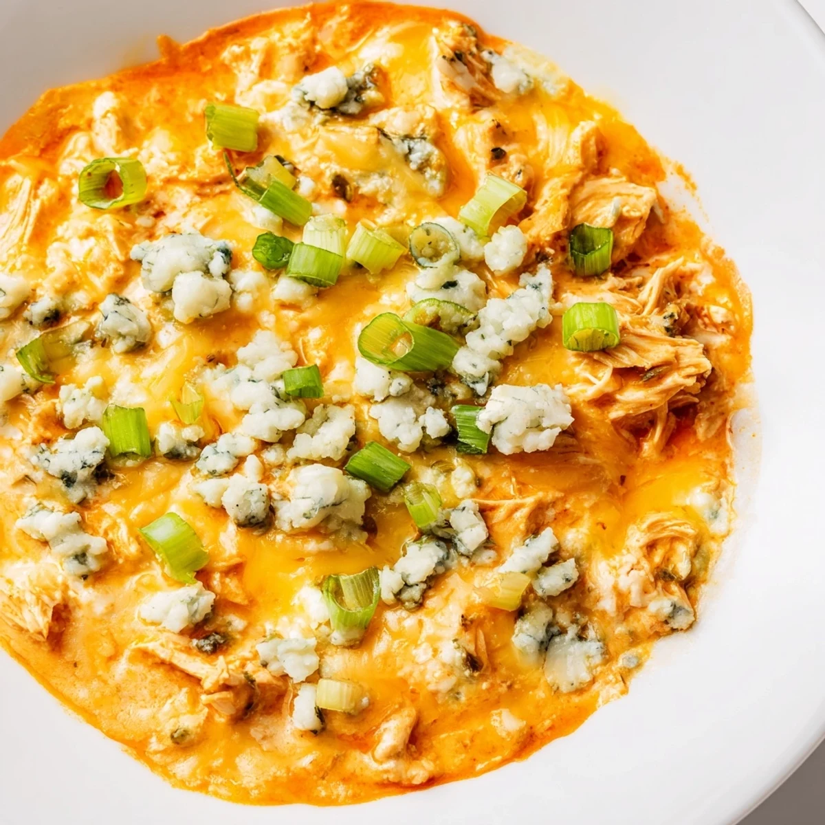 Keto Buffalo Chicken Dip in a ceramic dish, garnished with green onions and crumbled blue cheese.