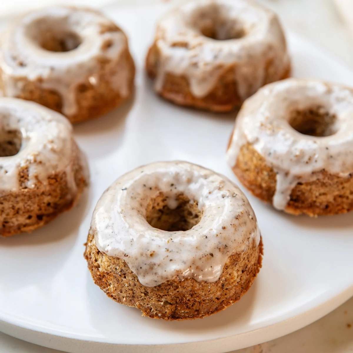 Stack of golden Baked Banana Bread Donuts, lightly dusted with powdered sugar, ready to be enjoyed as an afternoon snack.