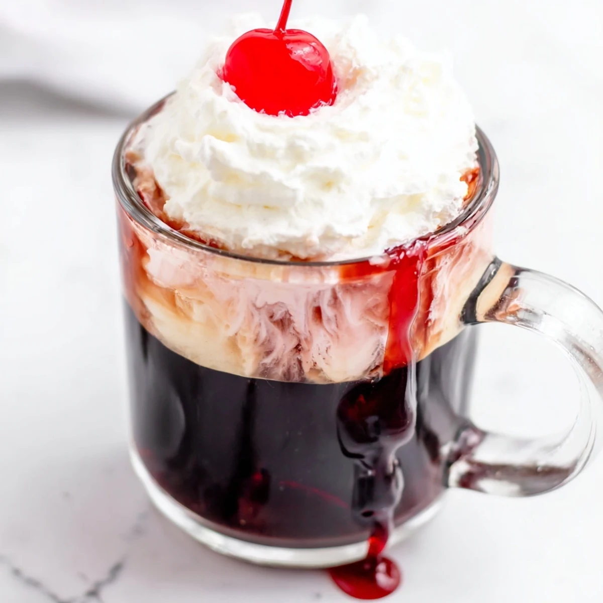 A steaming cup of Viral Cherry Vanilla Latte topped with whipped cream and fresh cherries on a wooden table.