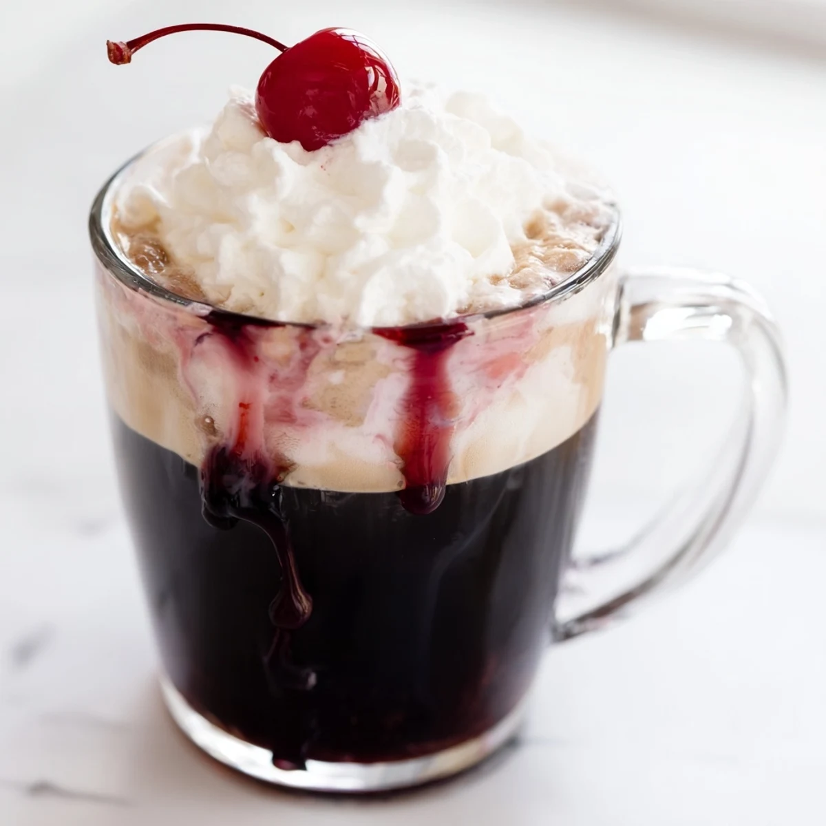 Close-up of a Viral Cherry Vanilla Latte garnished with a maraschino cherry and a drizzle of cherry syrup.