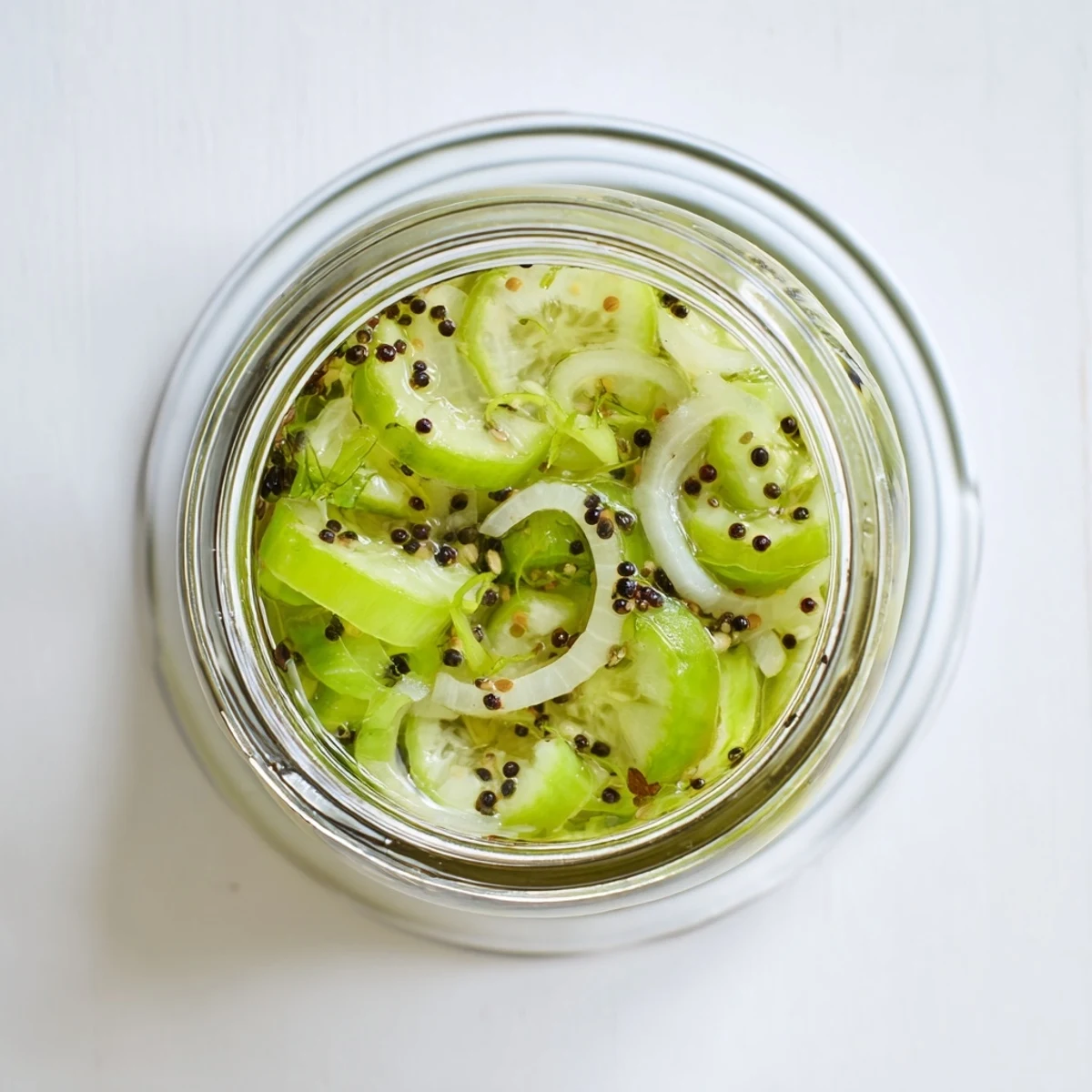 Bright Quick Pickled Celery in a jar, with thin slices of celery and shallots in a tangy brine.