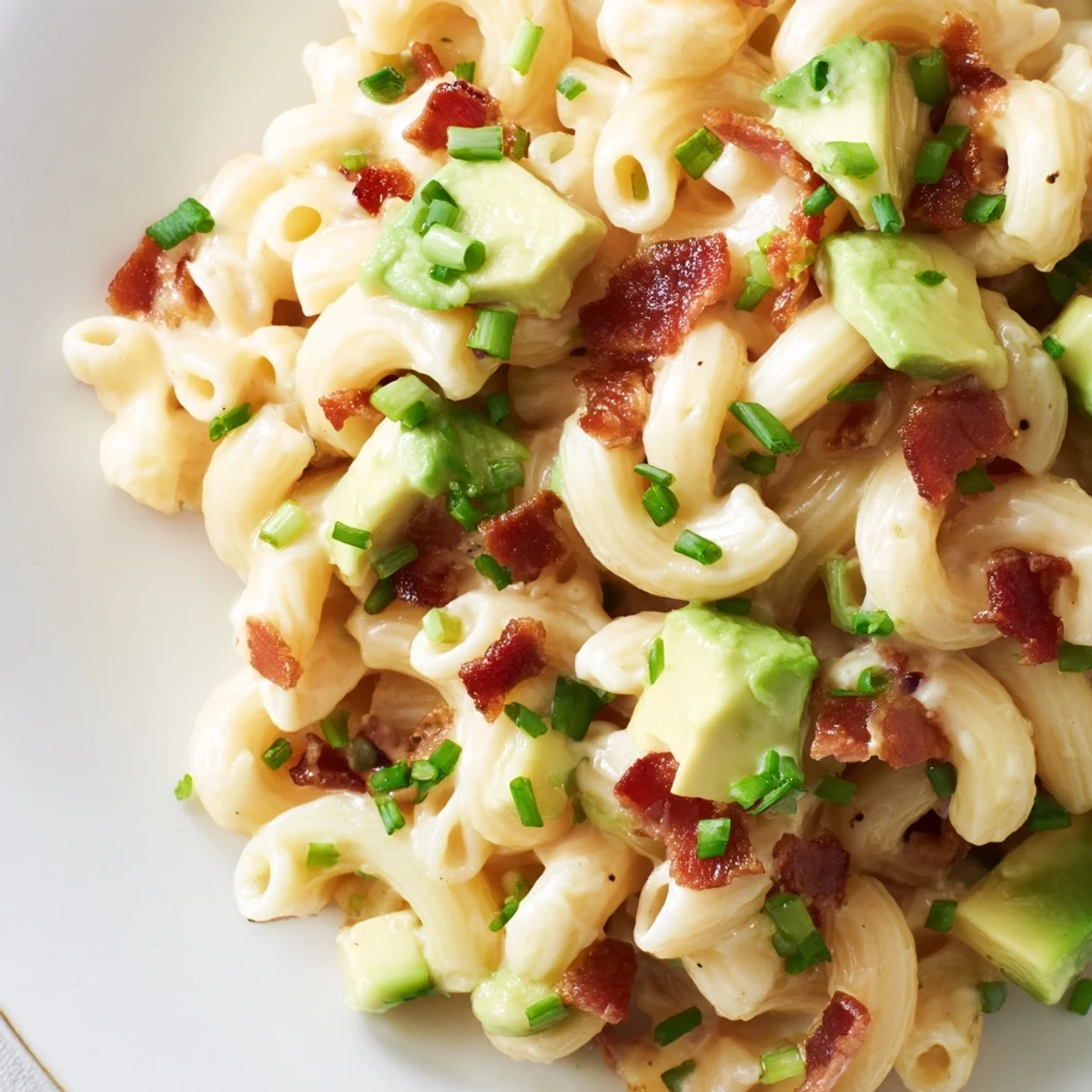 Hearty Avocado and Bacon Mac and Cheese garnished with green chives and bacon, ready to serve for dinner.