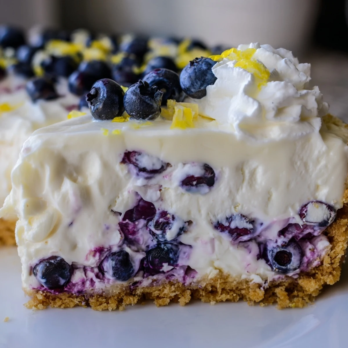 Summer dessert featuring chilled no bake lemon blueberry cream cake with graham cracker base and fruit topping