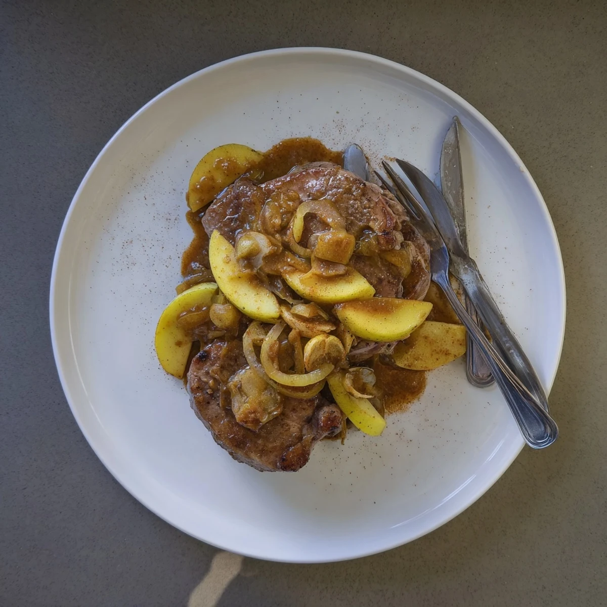 Golden brown pork chops nestled in a rich apple butter sauce with tender caramelized apples and onions