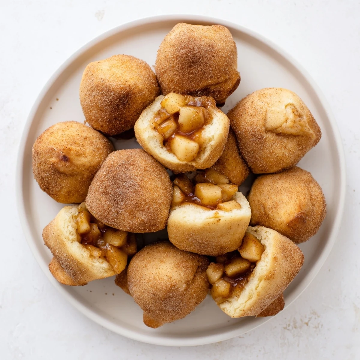 Golden caramel apple pie bombs with cinnamon sugar coating on a baking sheet