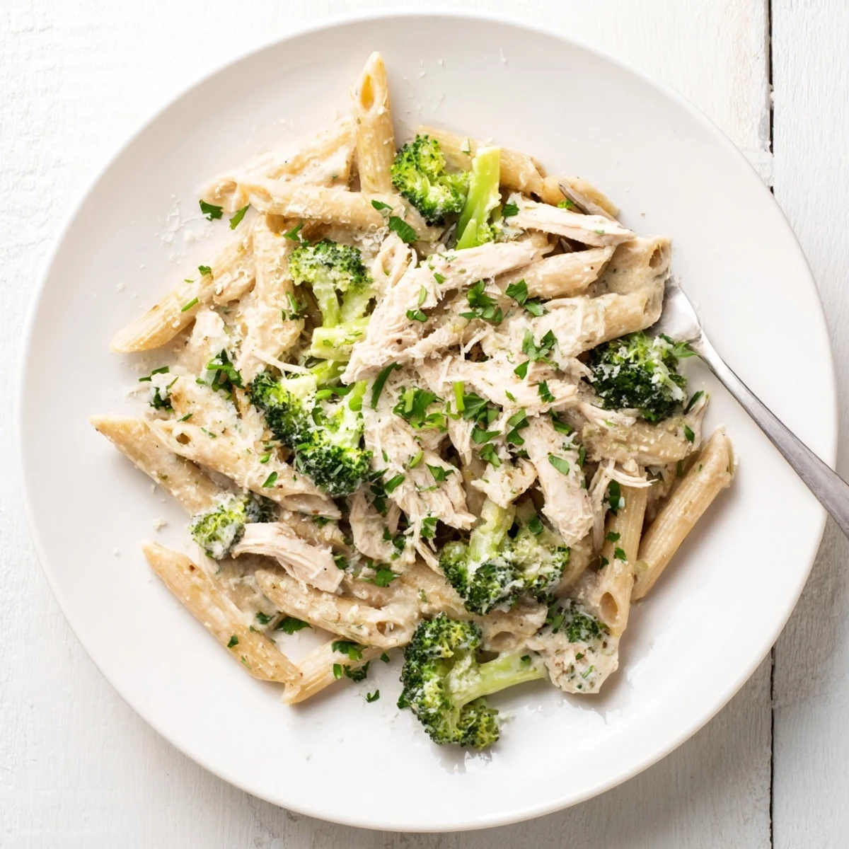 Golden rotisserie chicken broccoli pasta in rich white sauce topped with extra grated Parmesan cheese
