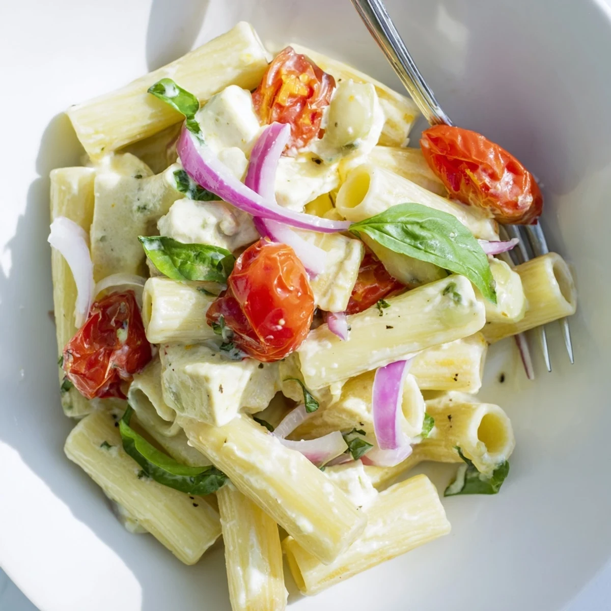 Golden baked feta cheese block melting over cherry tomatoes in this creamy pasta
