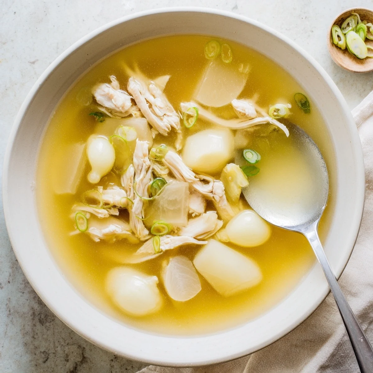 Comforting Dakgomtang soup bowl with succulent chicken pieces, aromatic broth, and vibrant green onion garnish