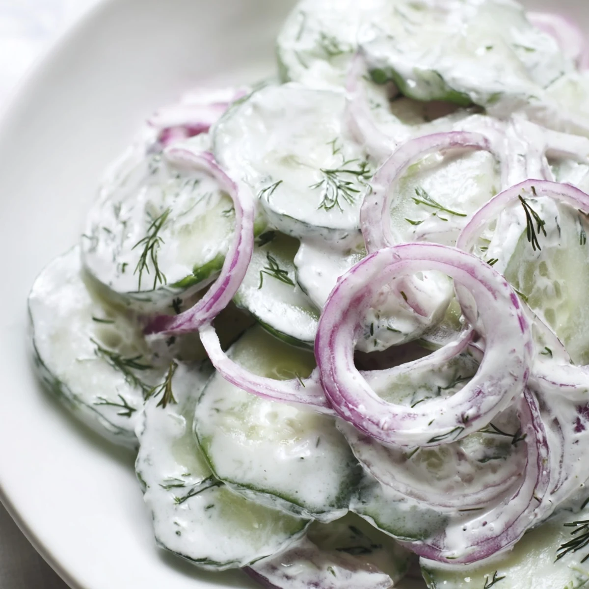 Creamy cucumber side dish with thinly sliced vegetables coated in herbed yogurt dressing