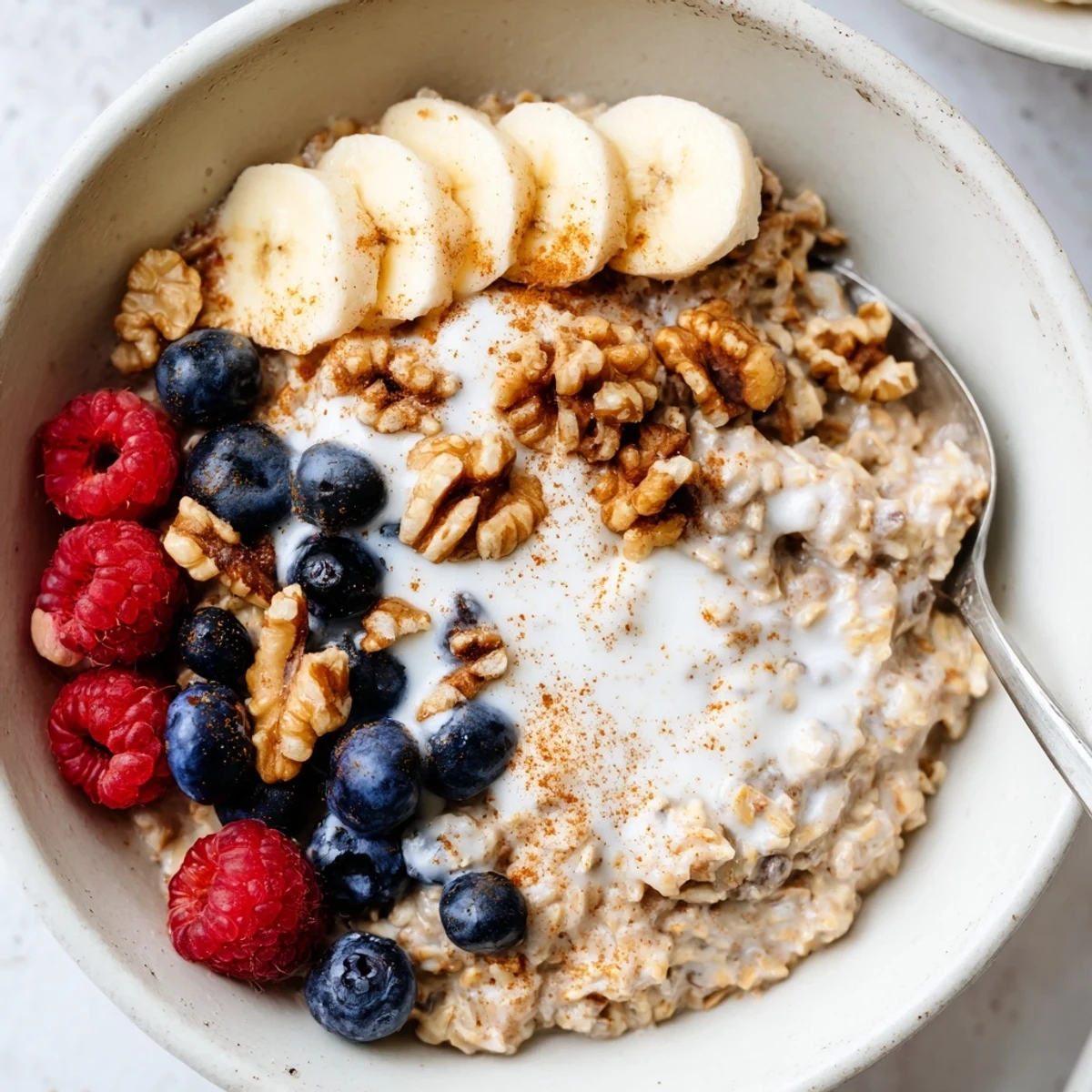 Creamy brown sugar overnight oats topped with fresh banana slices, crunchy walnuts, and vibrant berries in a glass jar.