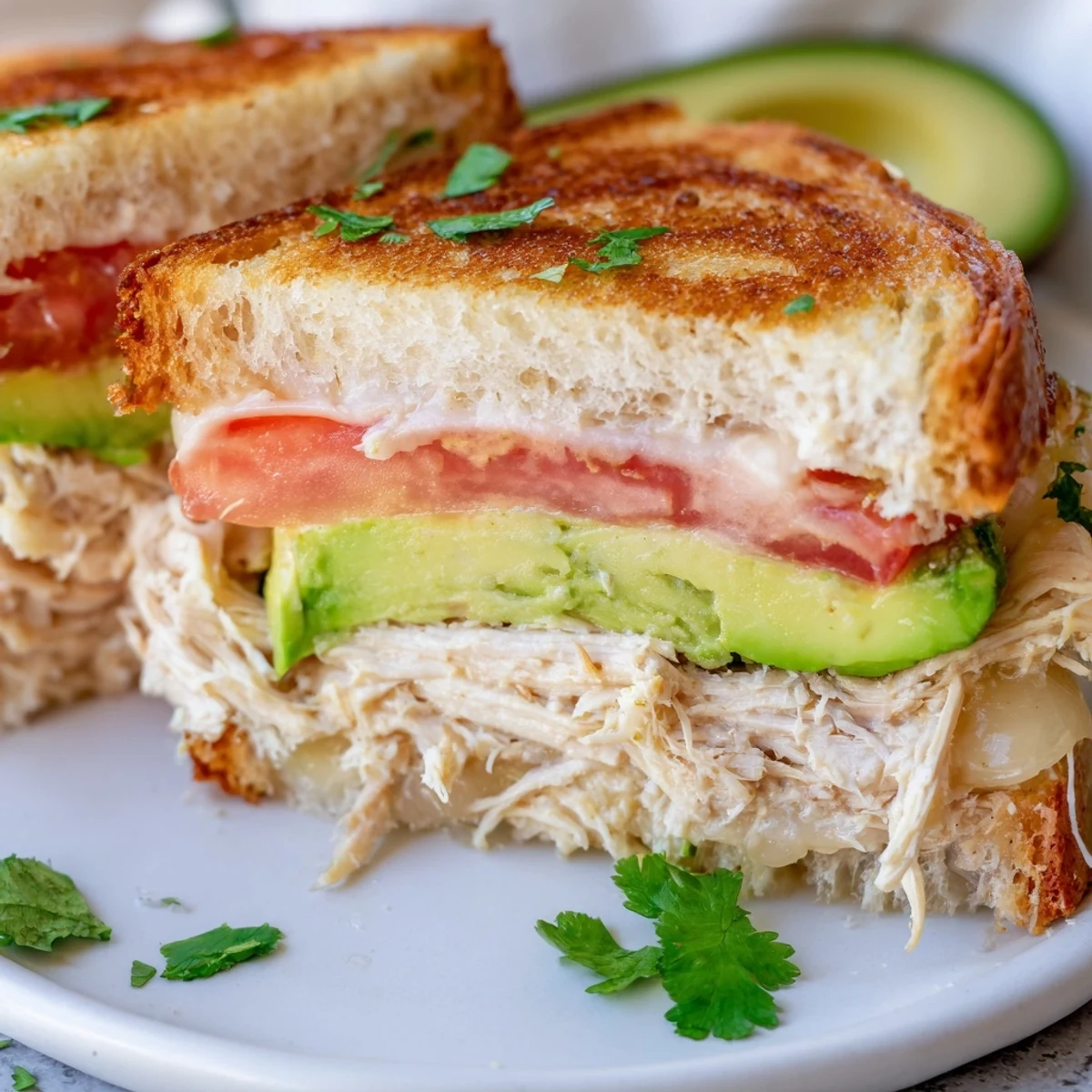 Sliced chicken avocado melt sandwich revealing layers of melted cheese, ripe avocado, and tender chicken between crispy bread