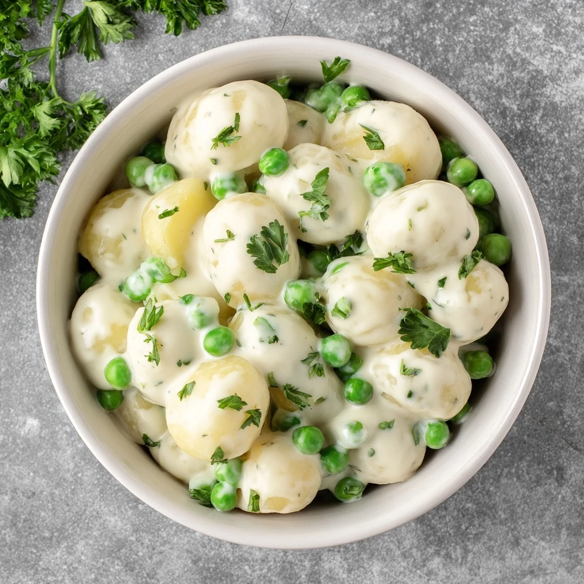Creamy peas and potatoes side dish served in a rustic ceramic bowl with herbs