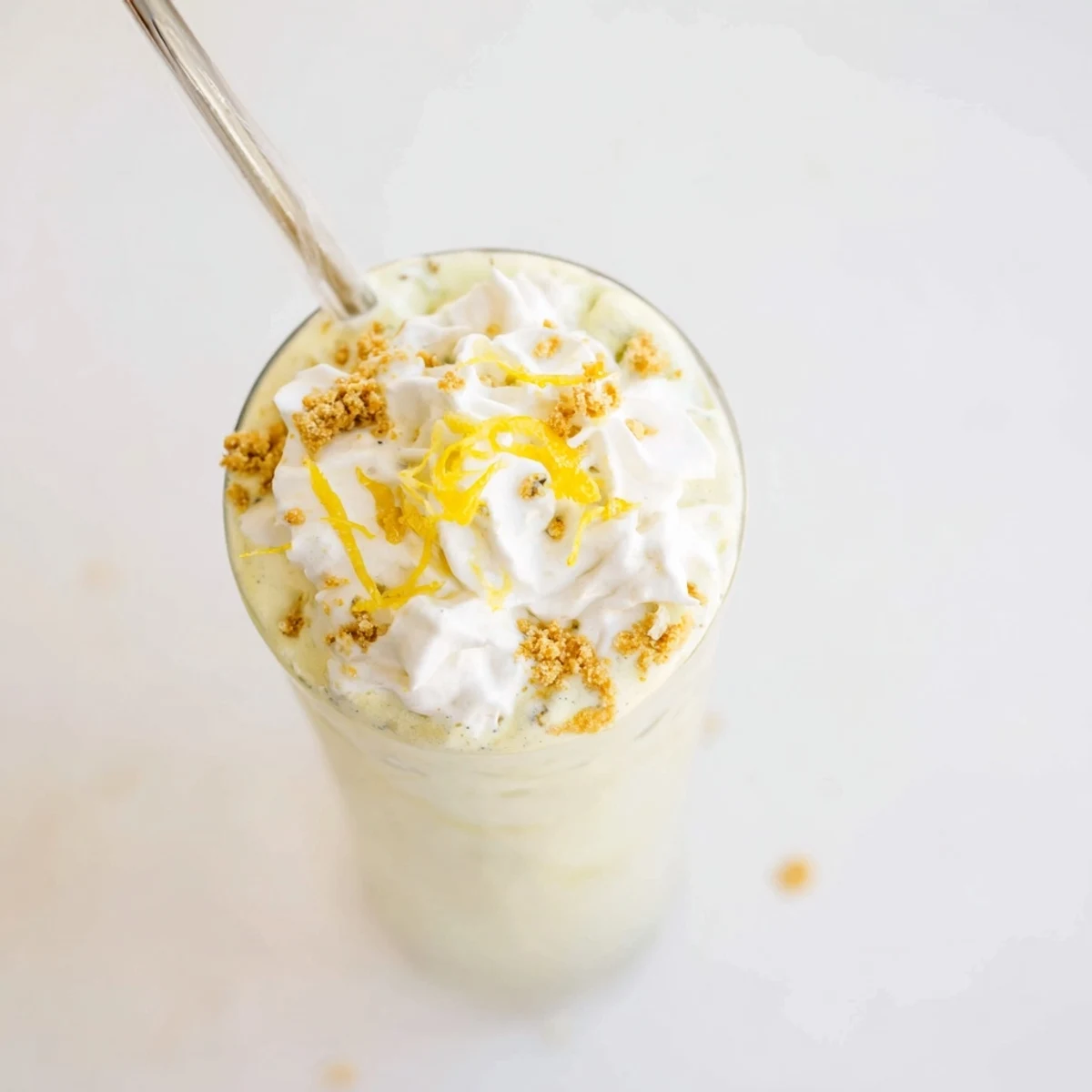 Refreshing lemon meringue frappé in a glass showing swirled yellow drink with white meringue peaks