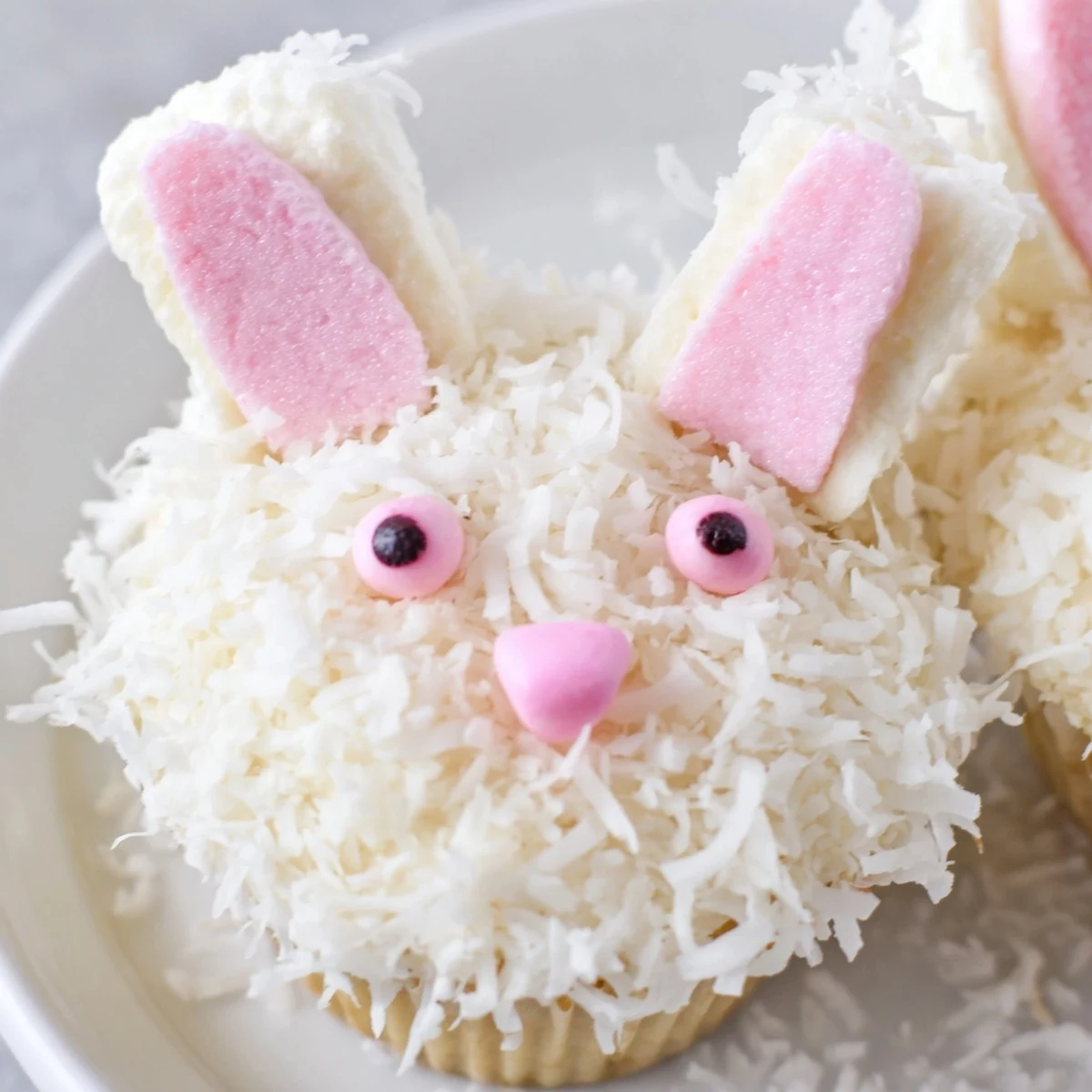 Adorable vanilla bunny cupcakes topped with coconut fur, marshmallow ears, and candy eyes