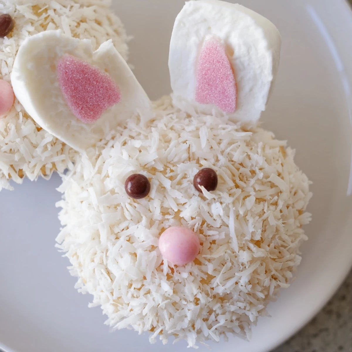 Easter bunny cupcakes decorated with pink marshmallow ears, jelly bean noses, and fluffy coconut