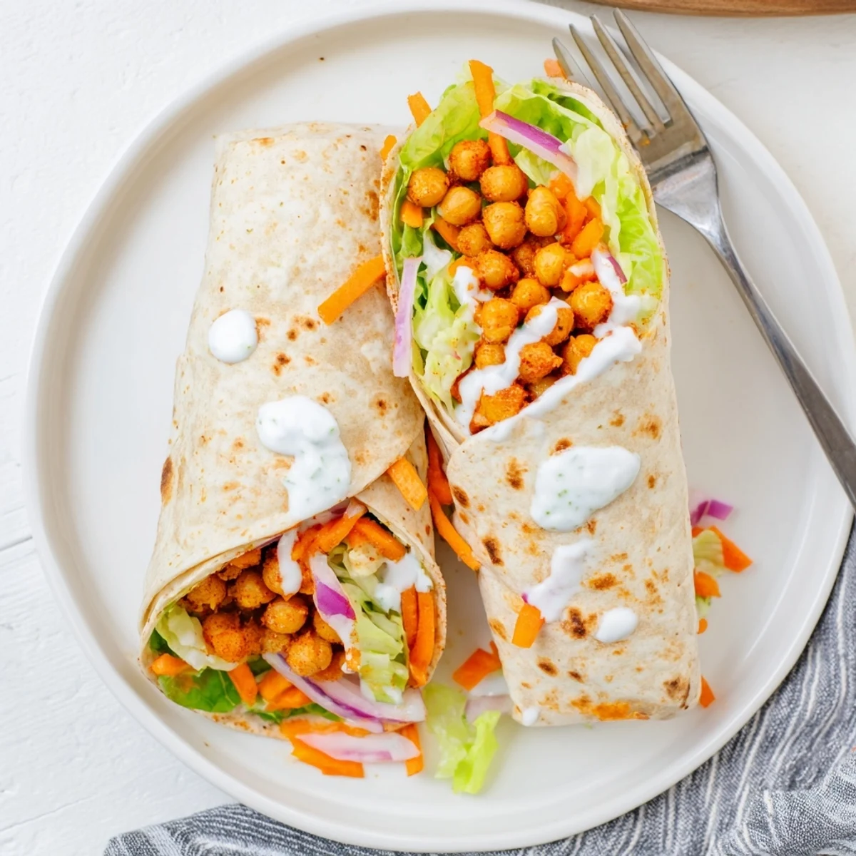 Warm buffalo chickpea wraps filled with crisp lettuce, carrots, and creamy ranch dressing