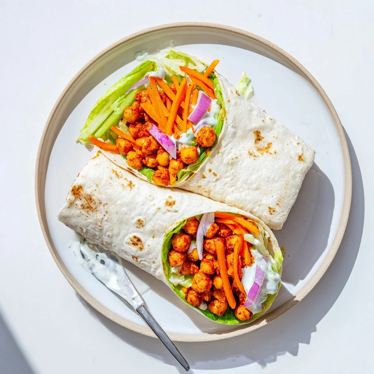 Spicy buffalo chickpea wraps rolled with fresh vegetables and tangy sauce for lunch