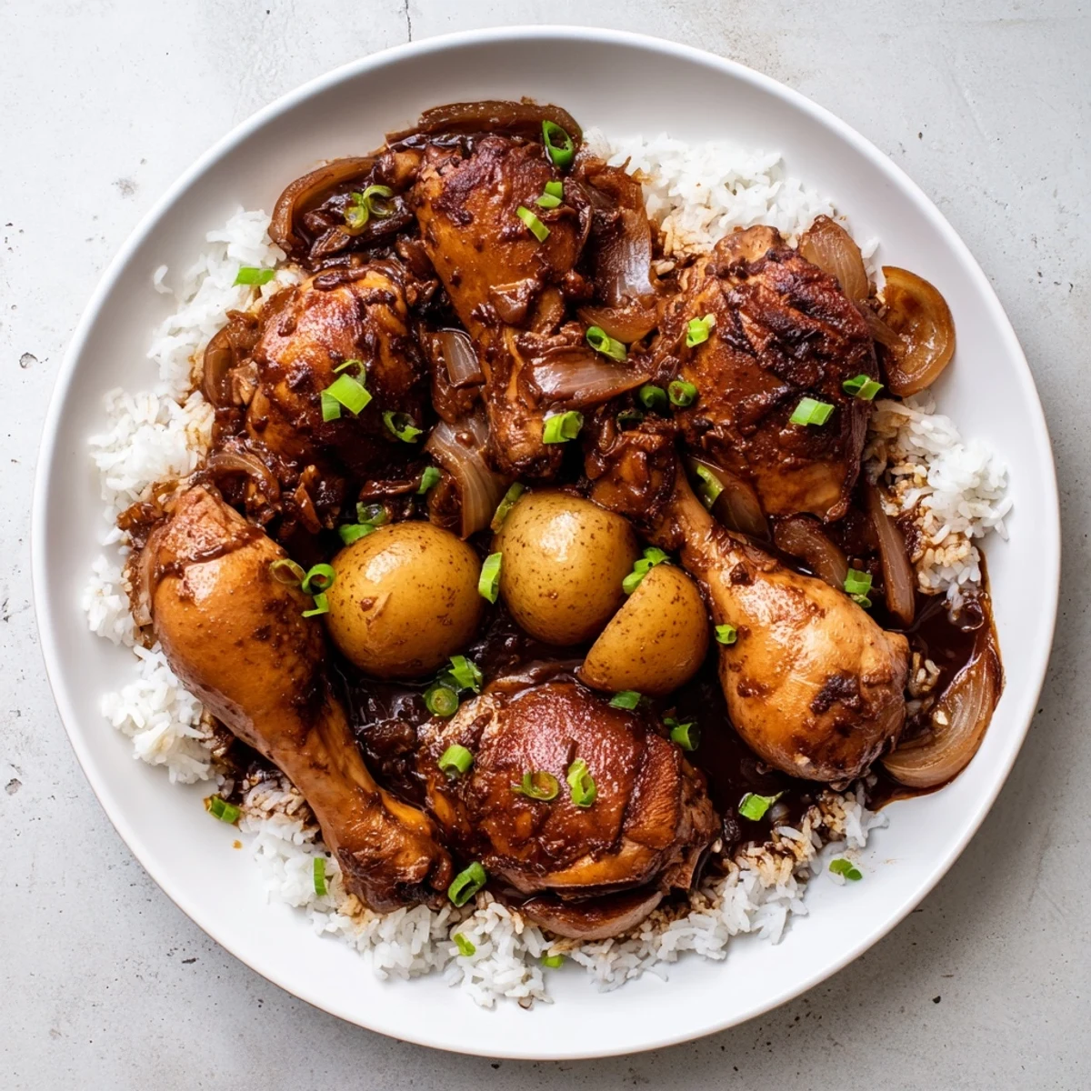 Tender chicken pieces simmered in tangy brown sauce garnished with green onions for Filipino Chicken Adobo