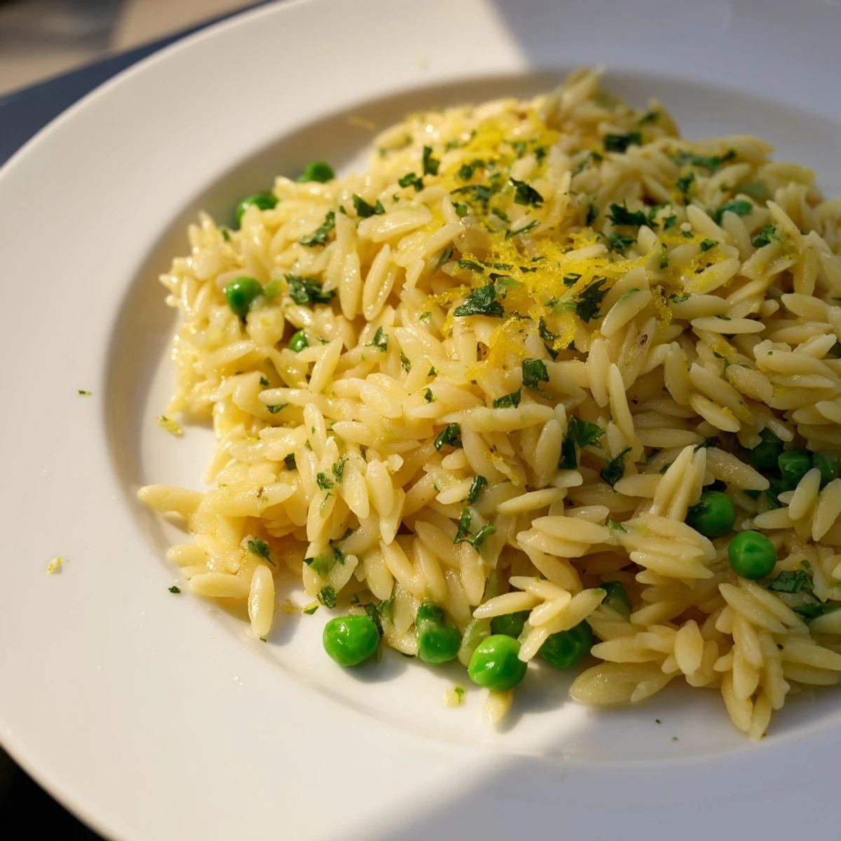 Golden lemon orzo pasta tossed with butter, parmesan and fresh green parsley in a white bowl