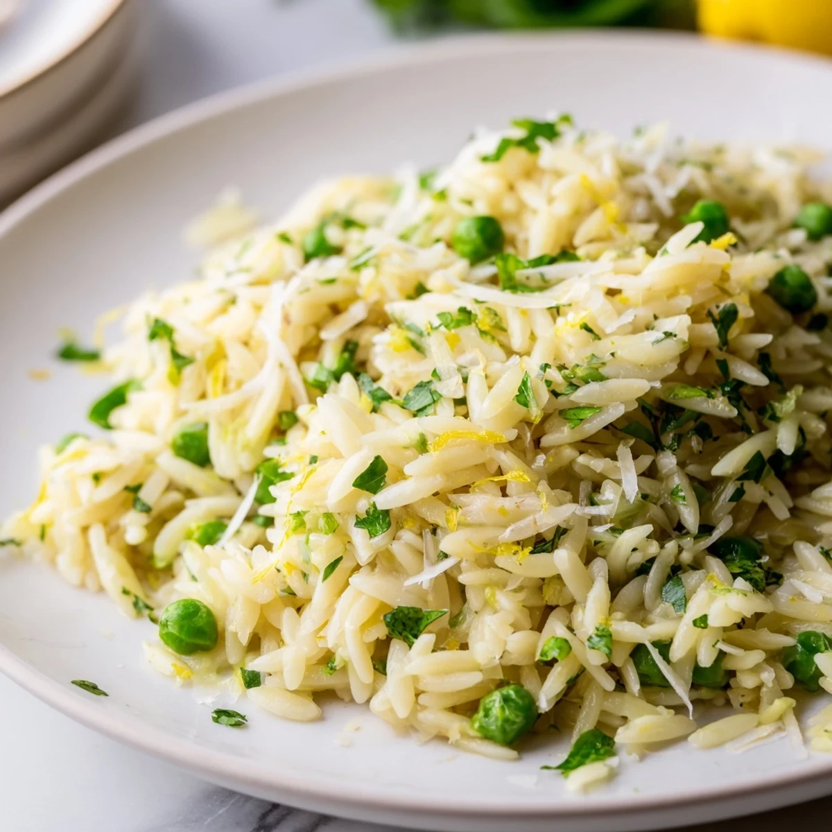 Simple lemon orzo dish with tender pasta, melted butter and chopped herbs garnished beautifully