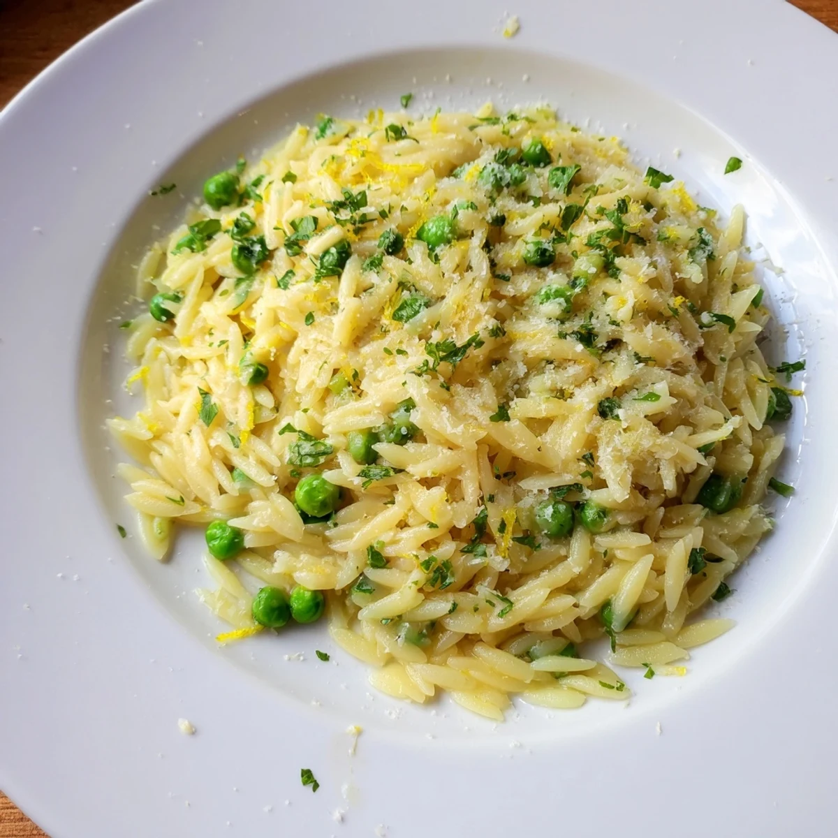 Creamy Mediterranean orzo with bright lemon zest and grated parmesan served on rustic wooden table