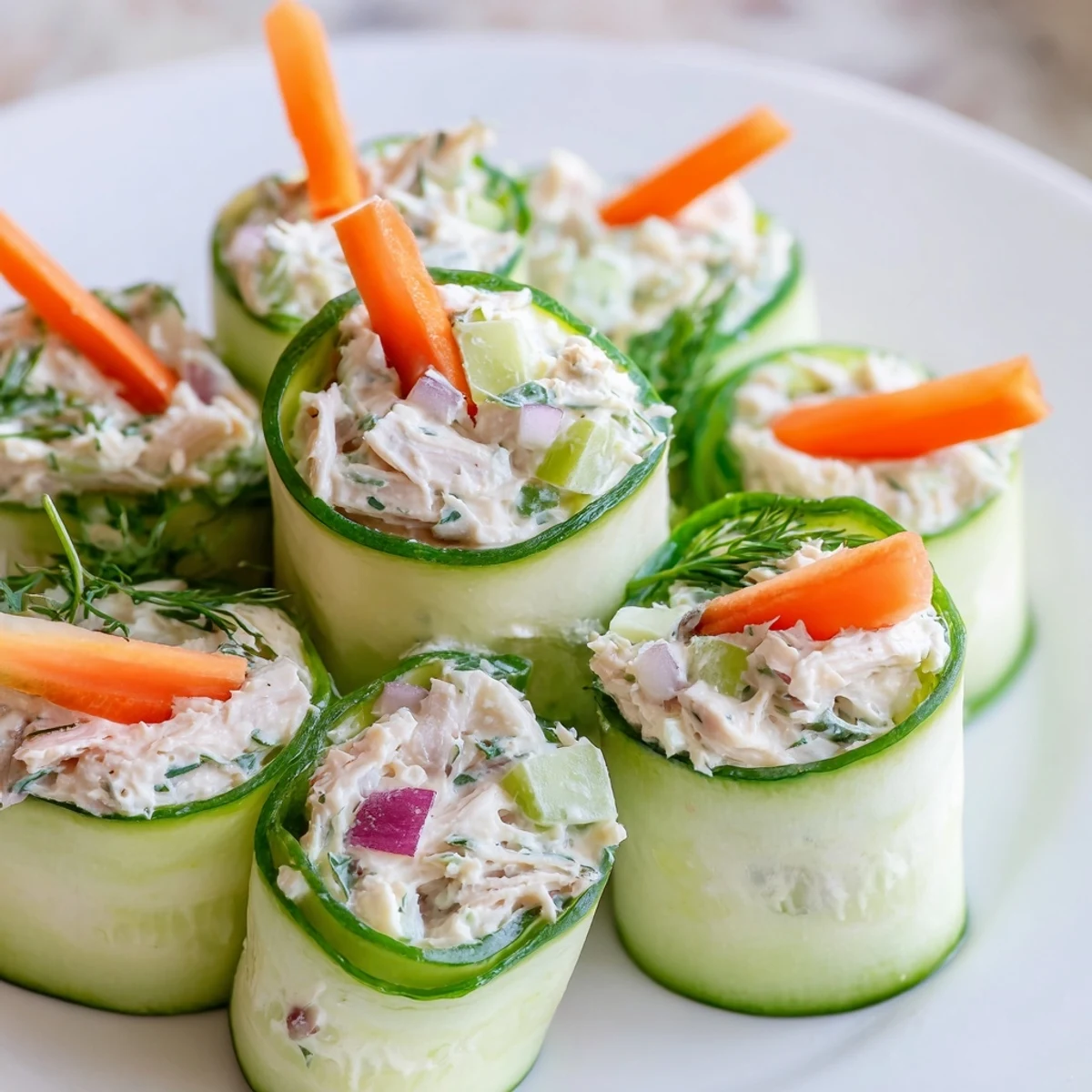 Crisp cucumber slices wrap savory chicken salad filling topped with bright julienned carrots