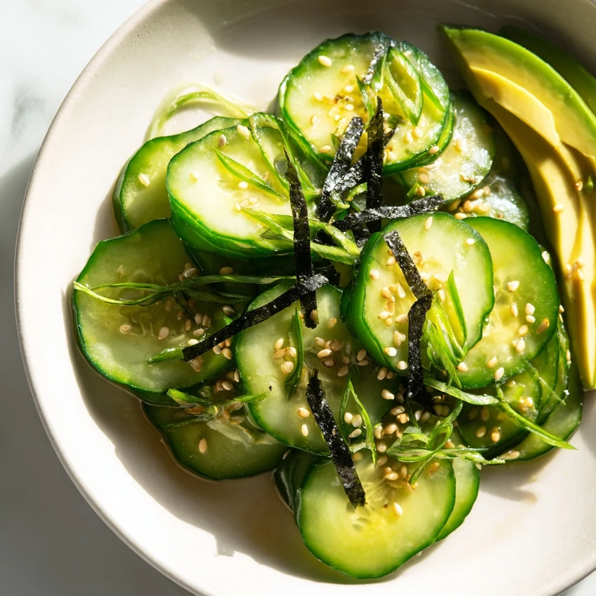 Refreshing sushi cucumber salad drizzled with sesame soy dressing in a serving bowl