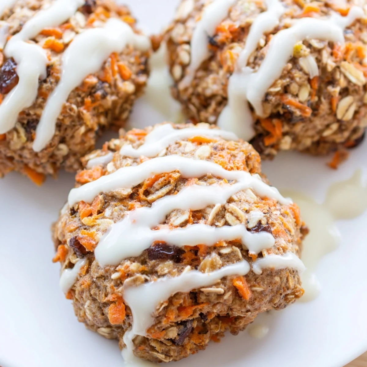 Golden carrot cake cookies topped with creamy white frosting on cooling wire rack