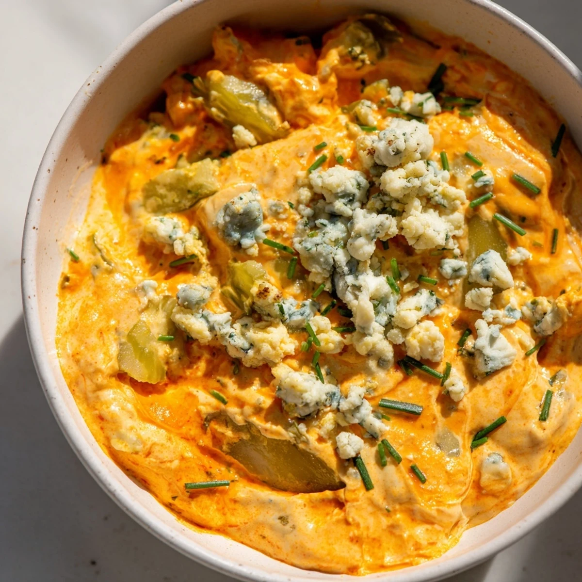 Tangy buffalo pickle dip topped with fresh chives and scattered pickle pieces