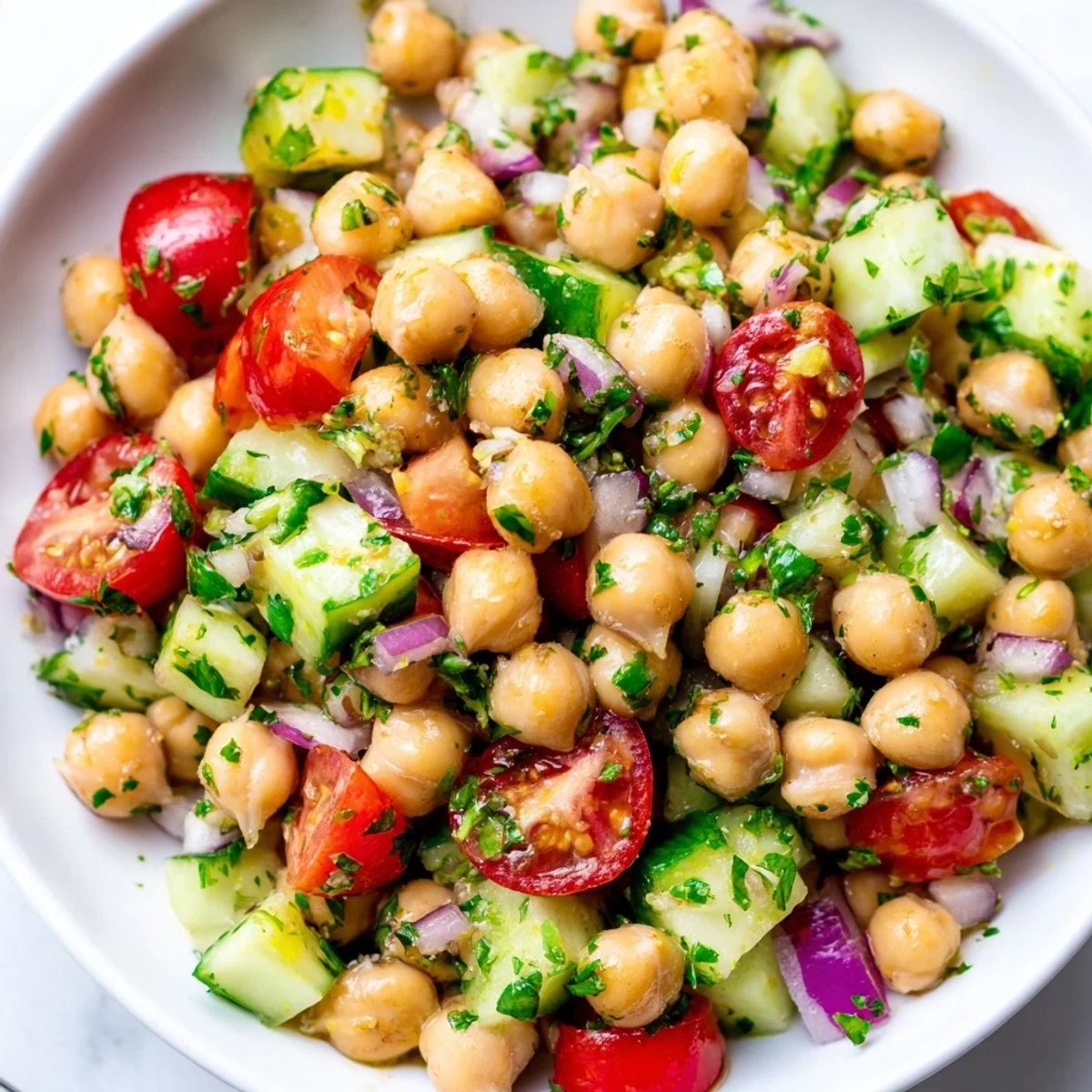 Chickpea cucumber salad in a white bowl with fresh herbs and lemon dressing