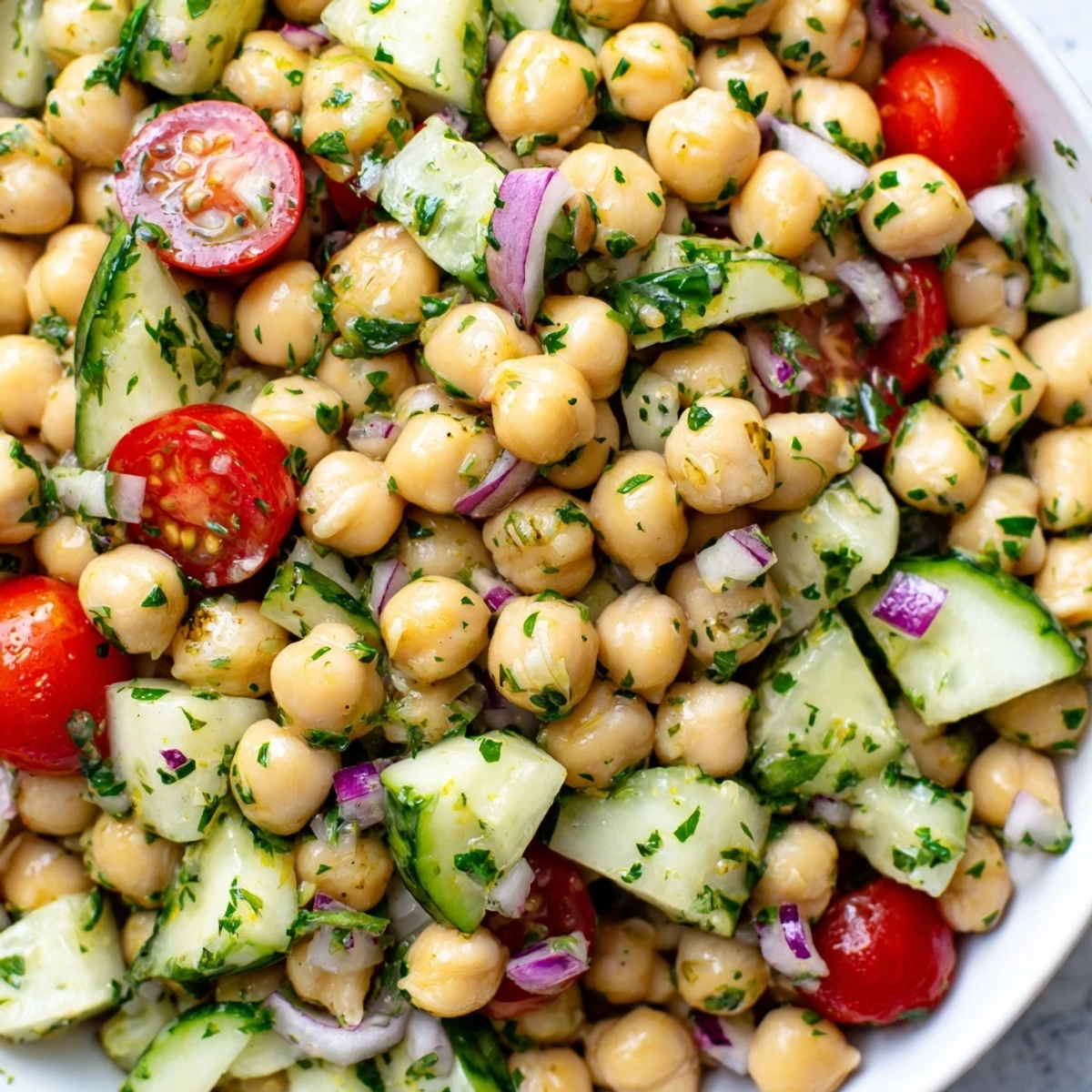 Colorful chickpea cucumber salad featuring ripe tomatoes, red onion, and bright parsley