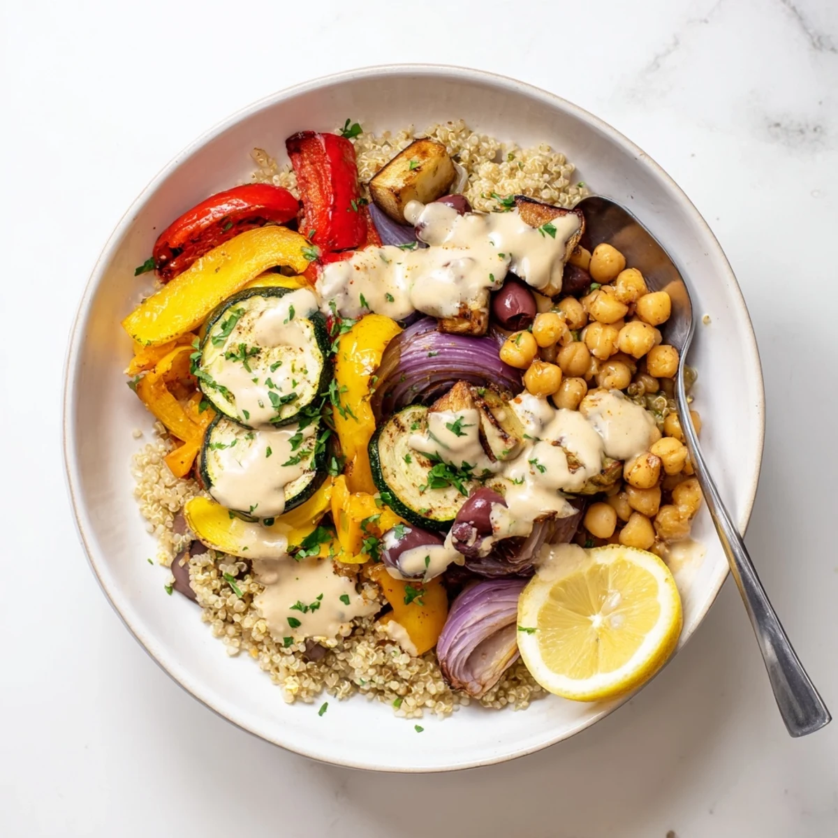 Warm vegan Mediterranean roasted vegetables bowl served over quinoa with chickpeas and a zesty lemon dressing.